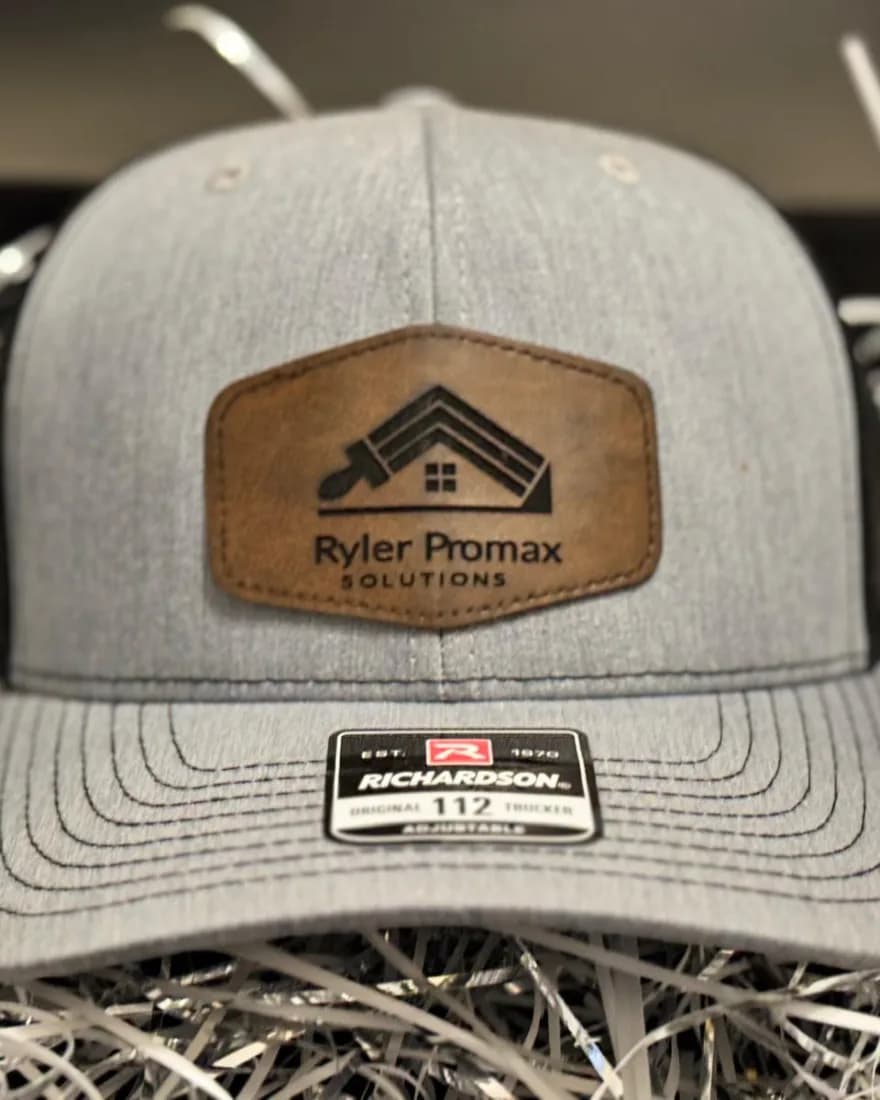 Heather grey trucker hat with a laser-engraved Ryler ProMax leather patch